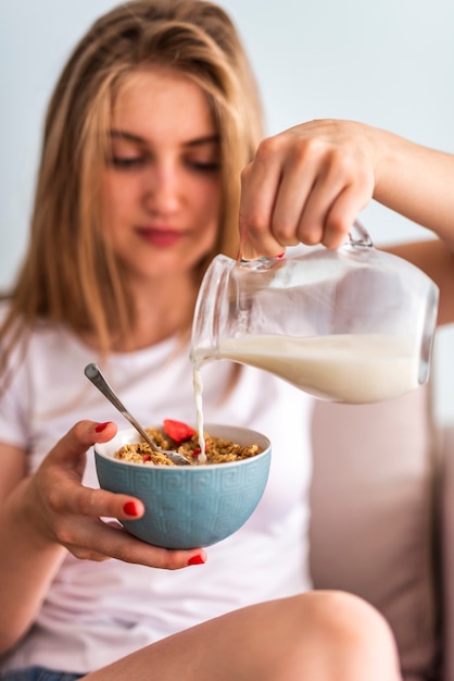 Latte di versamento della donna del primo piano in ciotola