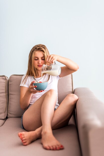 Latte di versamento della donna di vista frontale in ciotola