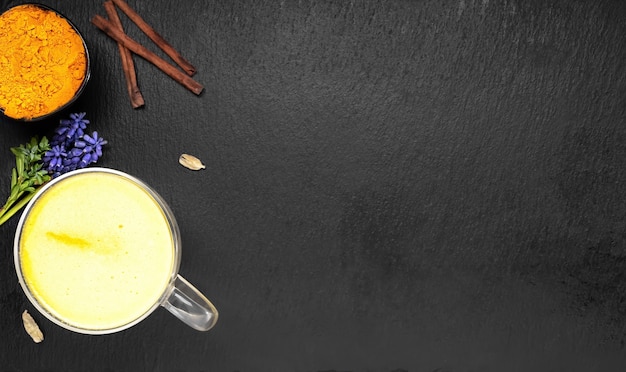 Latte dorato con curcuma e altre spezie su una superficie nera