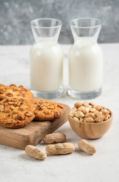 Latte fresco, arachidi e gustosi biscotti sul tavolo di marmo.