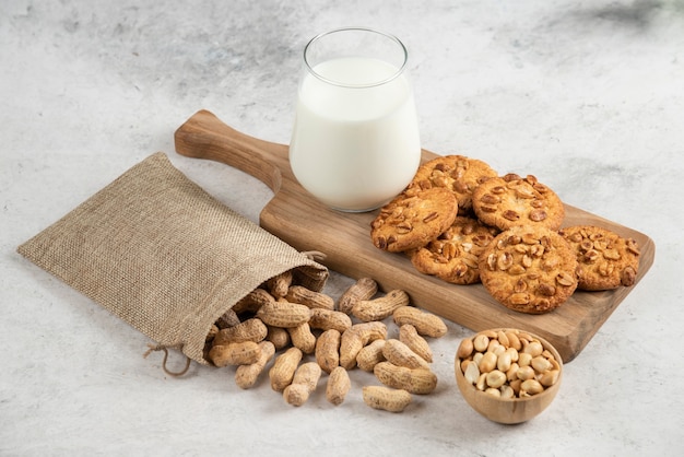 Latte fresco e biscotti su tagliere di legno con sacco di arachidi.