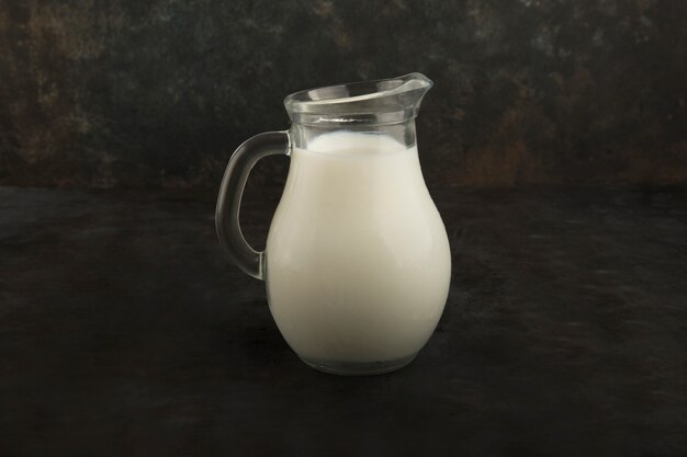 Latte fresco in un barattolo di vetro su sfondo nero