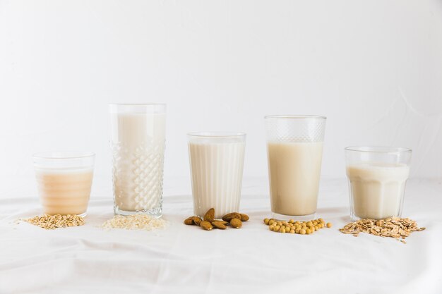 Latte in diversi tipi di bicchieri e cereali