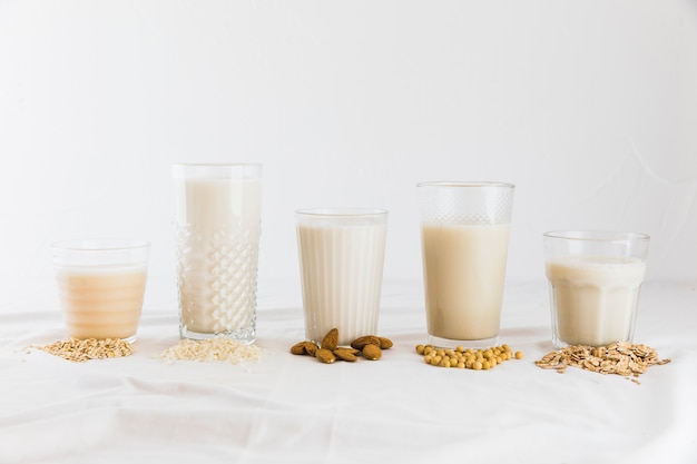 Latte in diversi tipi di bicchieri e cereali