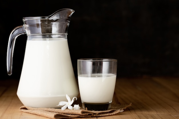 latte in vetro e brocca sul tavolo di legno