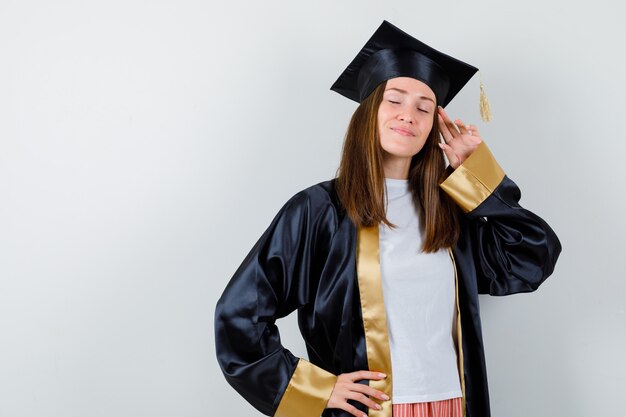 Laureato femminile in posa con le dita che toccano la testa in uniforme, abbigliamento casual e guardando rilassato, vista frontale.