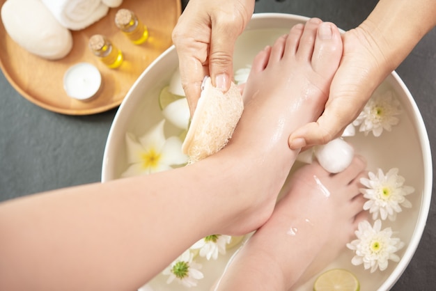 Lavaggio dei piedi nella spa prima del trattamento. trattamento termale e prodotto per piedi femminili e spa per le mani.