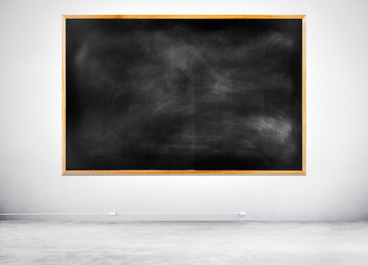 Foto gratuito lavagna nera vuota su un muro bianco