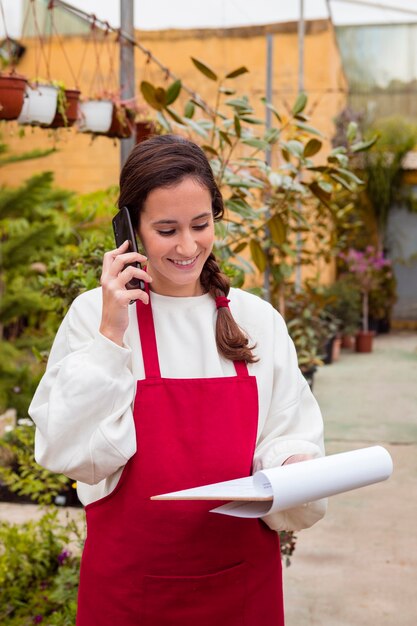 Lavagna per appunti della tenuta della donna e parlare al telefono in serra