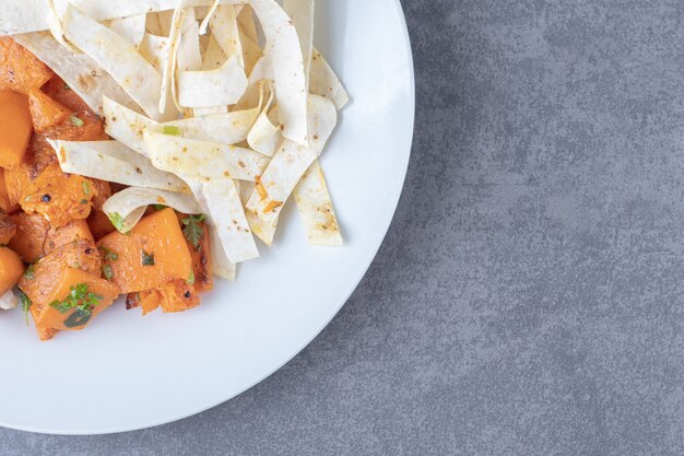 Lavash affettato delizioso e carota al forno nel piatto, sulla superficie di marmo.