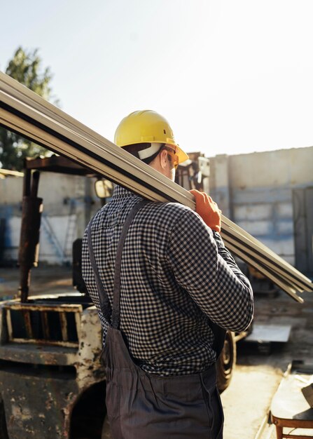 Lavoratore con cappello rigido che porta la legna