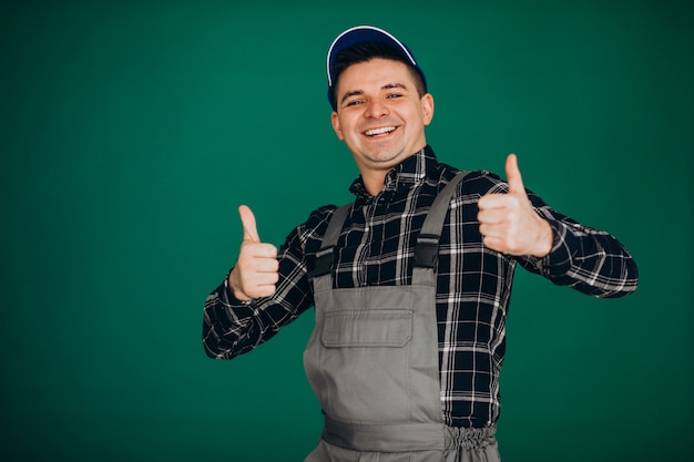 Lavoratore dell'uomo in cappello isolato sulla parete verde