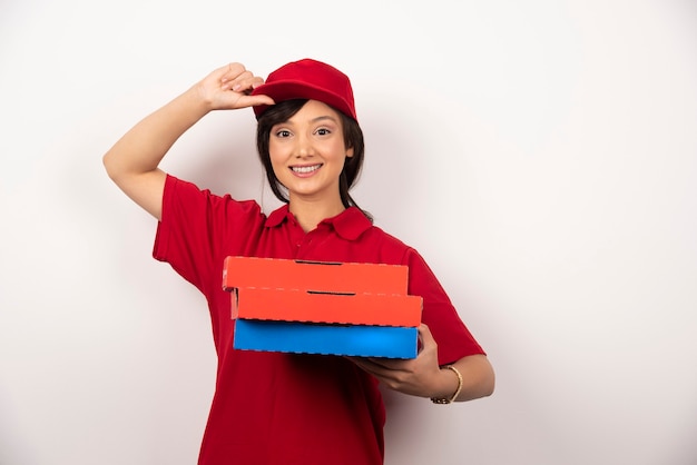 Lavoratore di consegna pizza femminile felice in piedi con tre cartoni di pizza.