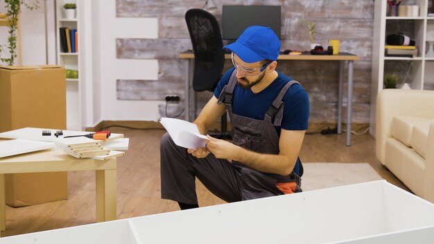 Lavoratore di sesso maschile che indossa occhiali di protezione prima del montaggio di mobili in appartamento. Operaio in dispositivi di protezione