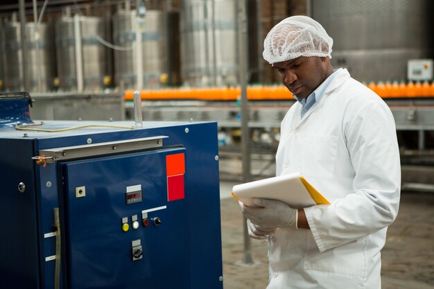 Lavoratore di sesso maschile che ispeziona le macchine alla fabbrica di succhi