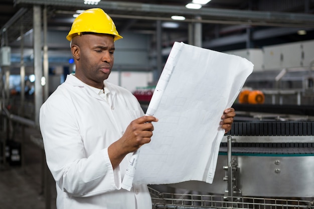 Lavoratore di sesso maschile che legge le istruzioni alla fabbrica di succhi