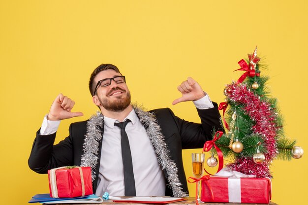 Lavoratore di sesso maschile di vista frontale seduto e celebrare il Natale al lavoro su giallo