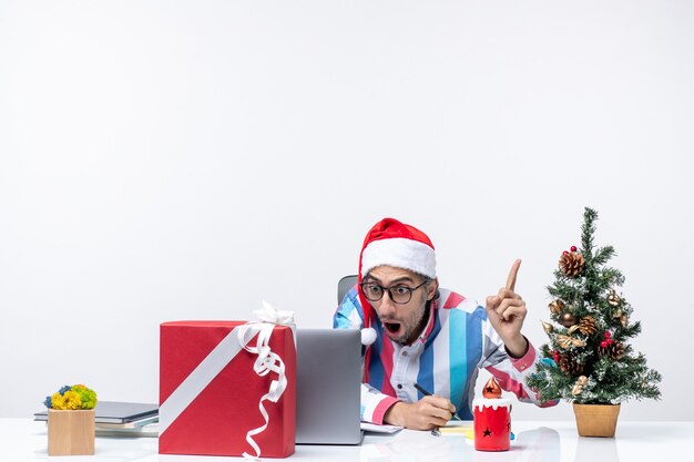 Lavoratore di sesso maschile vista frontale seduto al suo posto a scrivere note e utilizzare il lavoro di natale dell'ufficio delle emozioni del laptop