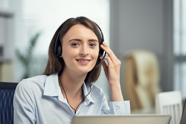 Lavoratore femminile caucasico felice della call center che sorride nell'ufficio