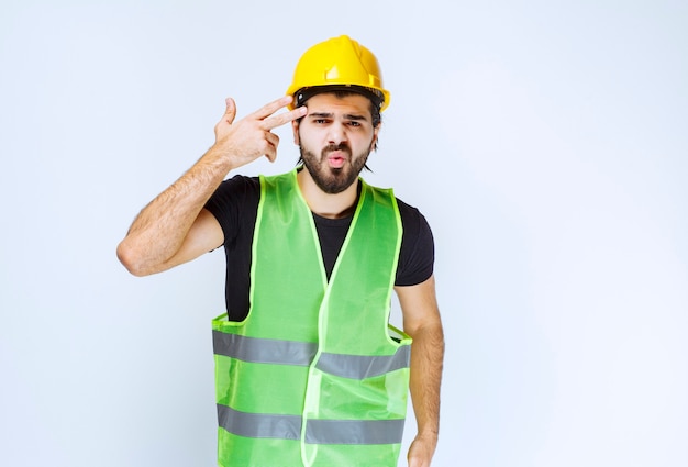 Lavoratore in casco giallo che pensa e sembra confuso.