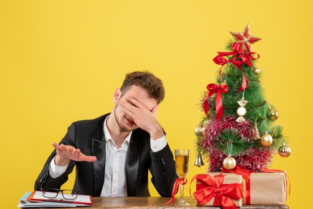 Lavoratore maschio vista frontale seduto dietro il suo posto di lavoro su giallo