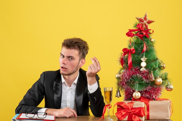 Lavoratore maschio vista frontale seduto dietro il suo posto di lavoro su giallo