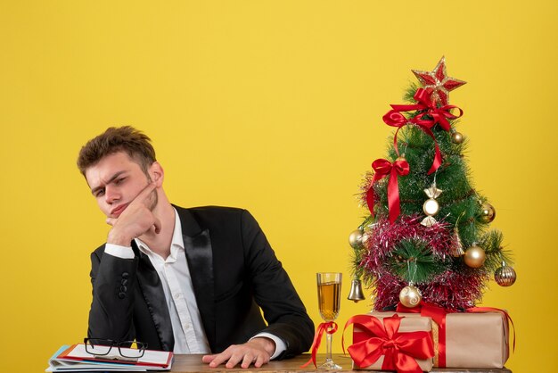 Lavoratore maschio vista frontale seduto dietro il suo posto di lavoro su giallo