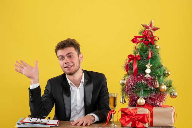 Lavoratore maschio vista frontale seduto dietro il suo posto di lavoro su giallo