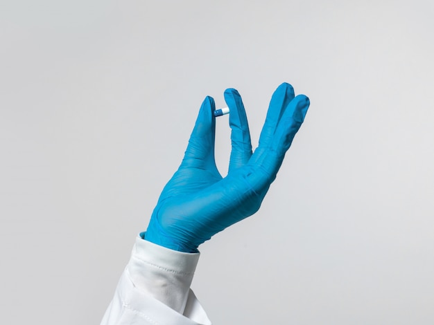 Lavoratore medico che tiene pillola blu in sua mano
