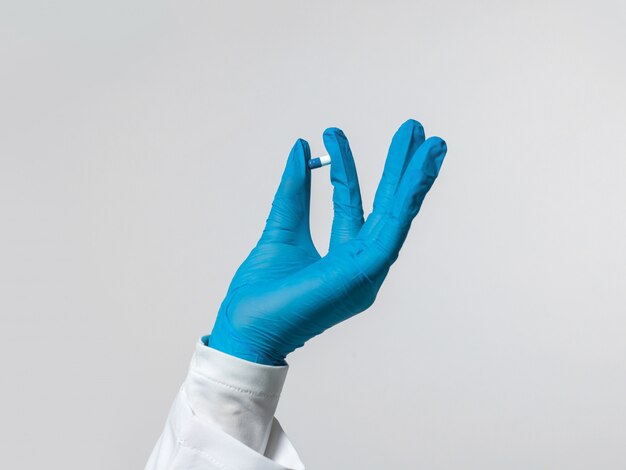 Lavoratore medico che tiene pillola blu in sua mano