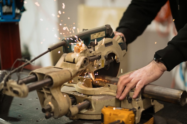 Lavoratore tecnico che taglia il metallo con molte scintille taglienti Utilizzo di attrezzature per il ferro da stiro