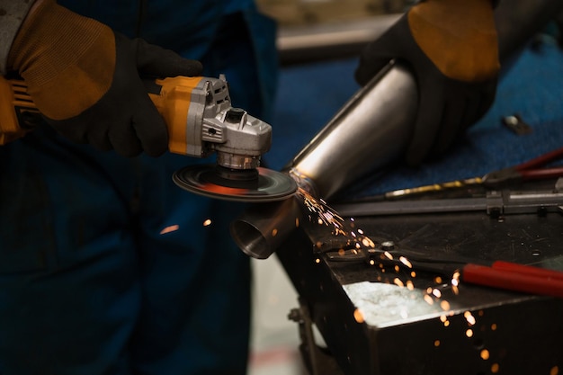 Lavoratore tecnico che taglia il metallo con molte scintille taglienti Utilizzo di attrezzature per il ferro da stiro