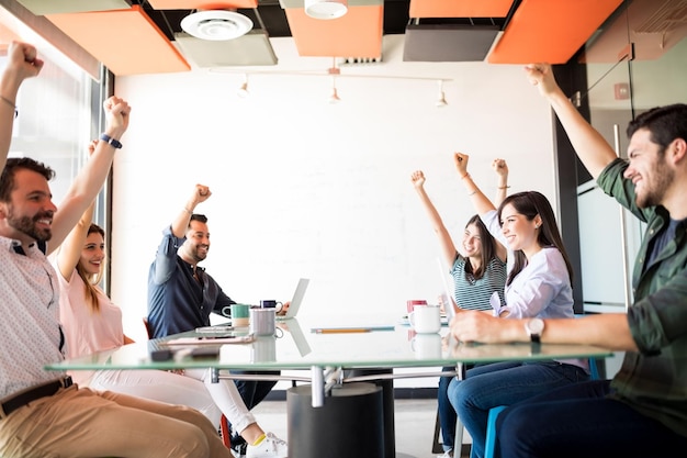 Lavoratori ambiziosi che tengono le mani alzate per mostrare il loro umore positivo durante le pause nella sala riunioni