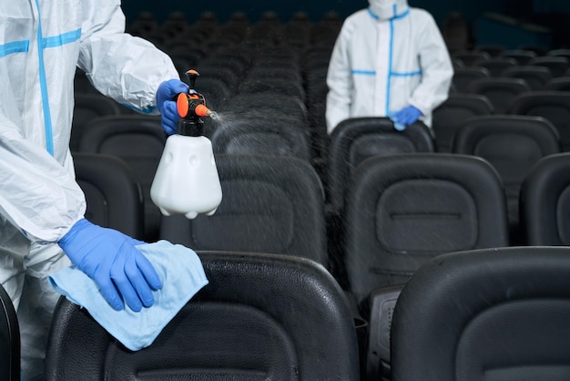 Lavoratori che puliscono sedie con disinfettanti al cinema