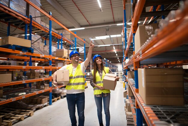 Lavoratori che trasportano scatole e trasferiscono i pacchi in una posizione appropriata sullo scaffale per una buona organizzazione presso il centro di stoccaggio