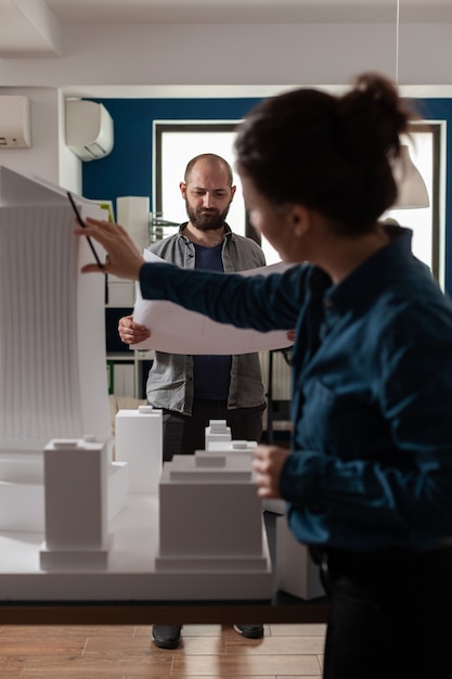 lavoratori di architettura che controllano i progetti con il modello di edificio maquette