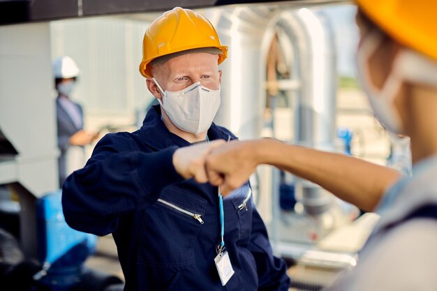 Lavoratori edili con maschere facciali che urtano i pugni durante l'epidemia di coronavirus