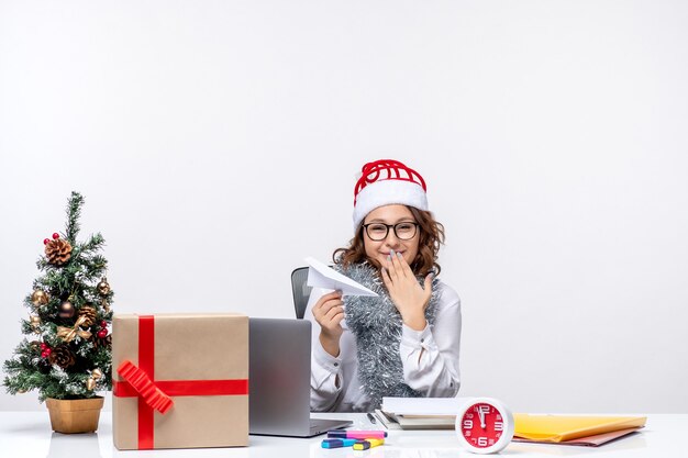 Lavoratrice vista frontale seduta davanti al suo posto di lavoro che gioca con aerei di carta