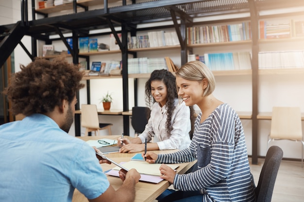 Lavoro collaborativo. Gruppo di giovani project manager che lavorano su nuove startup, piani di analisi. Tre giovani professionisti di prospettiva che si siedono nella biblioteca moderna sulla riunione.