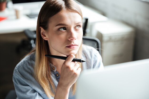 Lavoro serio della giovane donna in ufficio facendo uso del computer