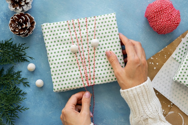 Lay piatto delle mani avvolgere lo spago attorno al regalo di Natale