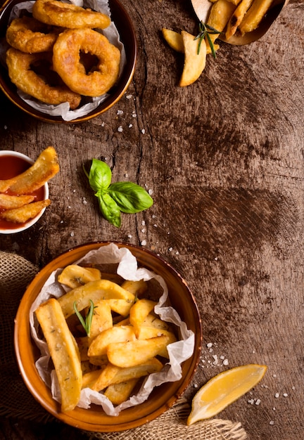 Lay piatto di patatine fritte in ciotole con sale e spazio di copia