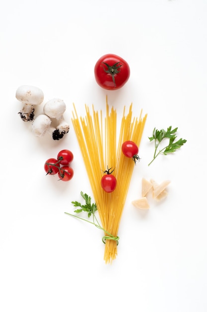 Lay piatto di spaghetti crudi ingredienti disposti come un bouquet sulla superficie bianca