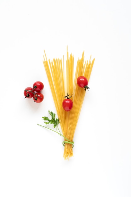 Lay piatto di spaghetti crudi ingredienti disposti come un bouquet sulla superficie bianca