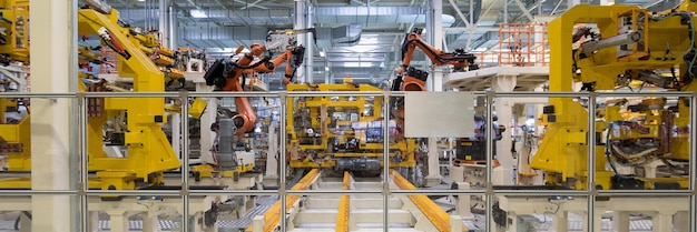 Le apparecchiature robotiche raccolgono le auto sulla linea di produzione Banner di fabbrica di automobili per riprese in formato lungo
