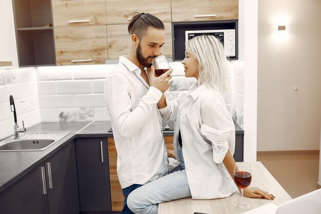 Le belle coppie bevono il vino rosso nella cucina