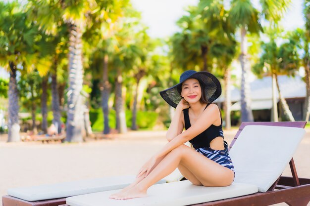 Le belle giovani donne asiatiche del ritratto si rilassano il sorriso felice intorno all'oceano della spiaggia del mare