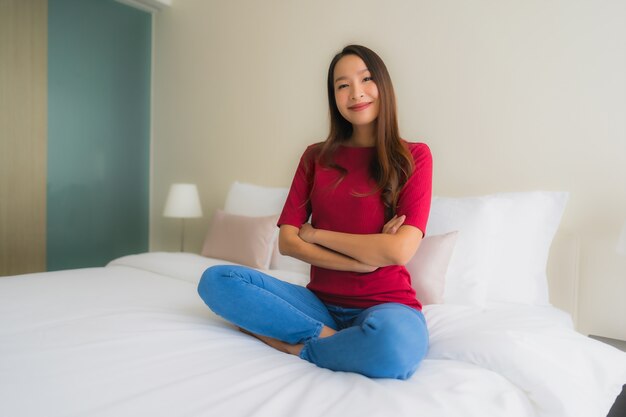 Le belle giovani donne asiatiche del ritratto sorridono felici sul letto