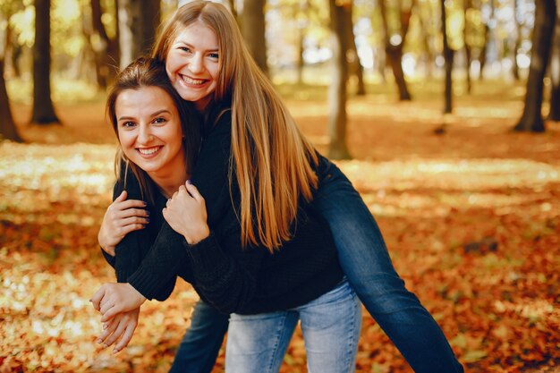 Le belle ragazze si divertono in un parco in autunno