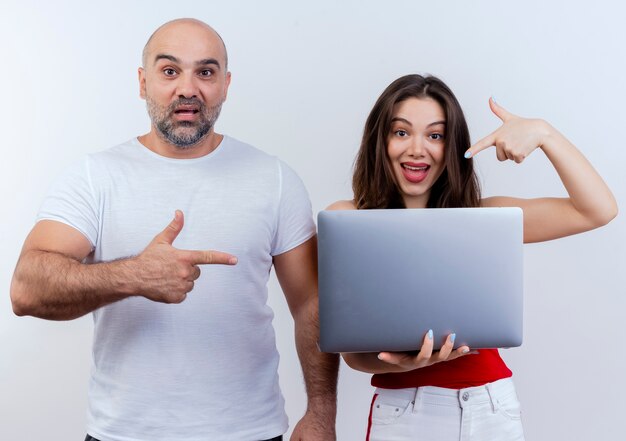 Le coppie adulte impressionate entrambi guardano il computer portatile della tenuta della donna ed entrambi che indicano al computer portatile